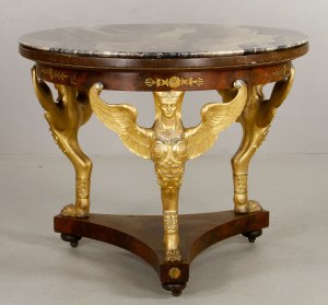 French Empire Style mahogany and ormolu center table, the three standards modeled as winged caryatid terms on lion claw feet, the apron embellished with bronze paterae detailed with anthemion sprays and laurel